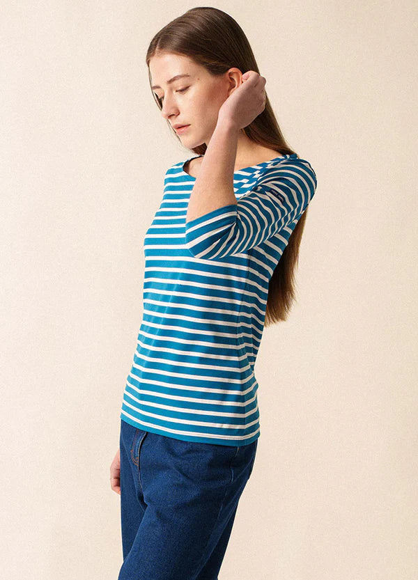 Frau mit langen braunen Haaren trägt das gestreifte Oberteil SAINT JAMES Garde-Cote marinière und Jeans, Blick nach unten.