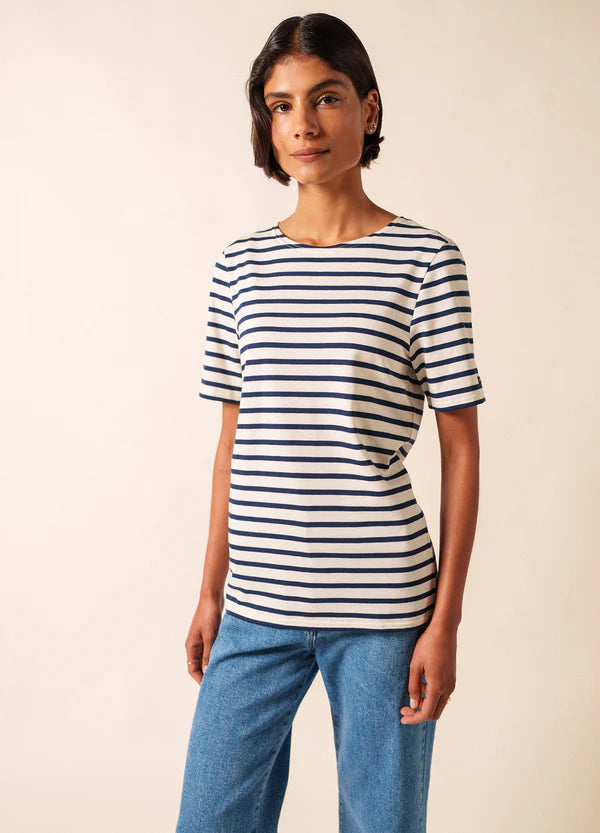 Person, die ein SAINT JAMES Levant Unisex-T-Shirt und blaue Jeans vor einem schlichten hellen Hintergrund trägt.