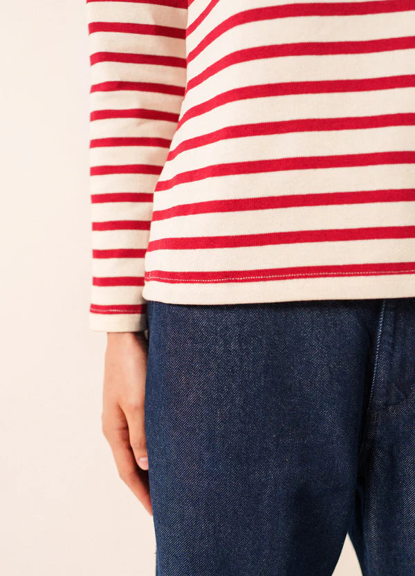 Person in einem rot-weiß gestreiften SAINT JAMES Meridame-Trikot mit blauen Jeans, Blick von der Schulter zur Hüfte.