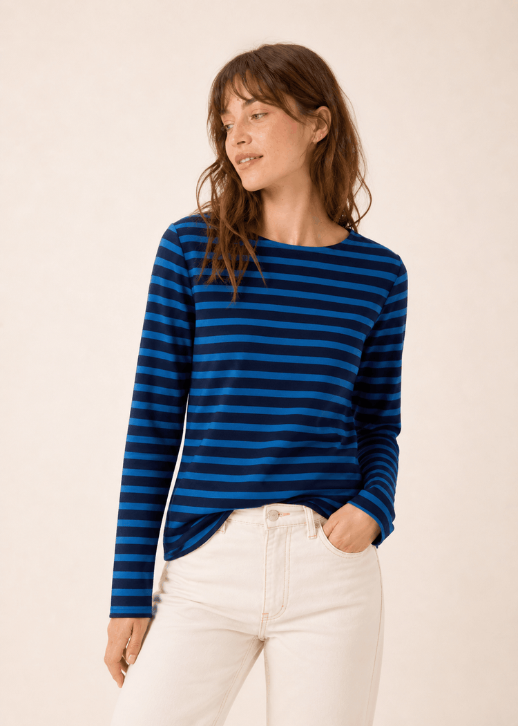 Frau in SAINT JAMES Meridame blau-schwarz gestreiftes Hemd, kardierte Baumwolle, mit hellen Jeans, Blick zur Seite.