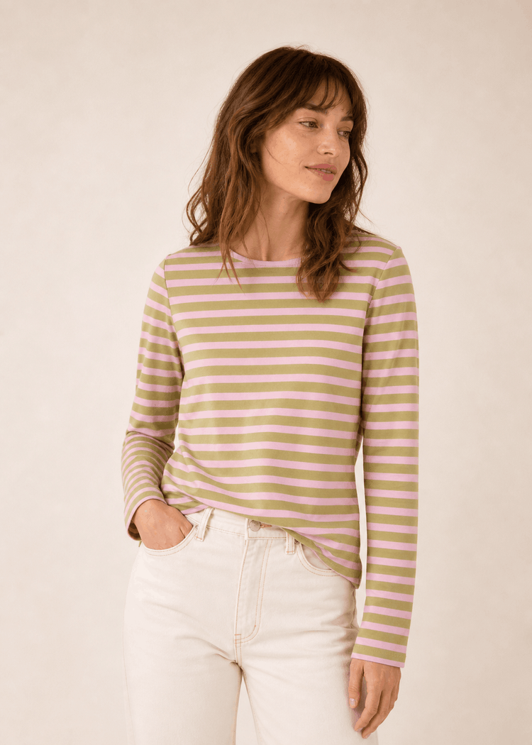 Frau in einem grün und lavendelfarben gestreiften SAINT JAMES Meridame-Shirt und hellen Jeans, die zur Seite schaut.