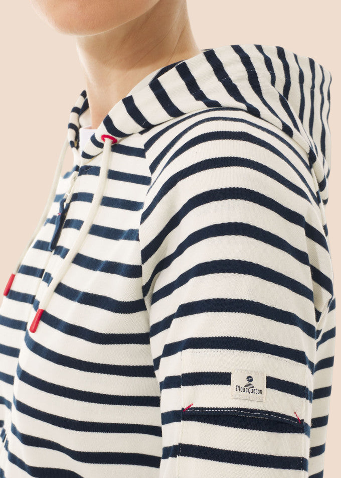 Frau trägt den MOUSQUETON Mulane Kapuzenpullover aus Baumwolle mit marineblauen Streifen und einer kleinen Ärmeltasche.