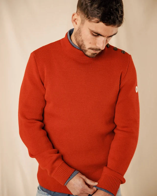 Ein Mann trägt den Pullover „ROYAL MER Adrian“ mit Schulterknöpfen und blickt vor einem beigen Hintergrund nach unten.