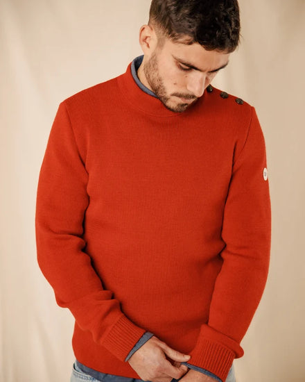 Ein Mann trägt den Pullover „ROYAL MER Adrian“ mit Schulterknöpfen und blickt vor einem beigen Hintergrund nach unten.