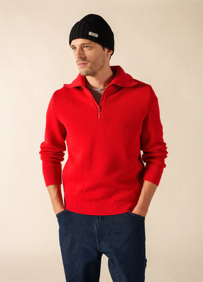 Mann in SAINT JAMES Barbaresque Pullover mit rotem Reißverschluss, schwarzer Mütze und blauer Jeans mit Händen in den Taschen.