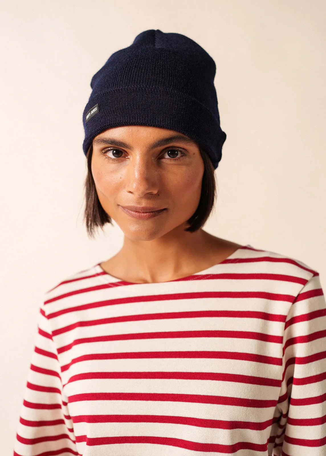 Frau trägt ein marineblaues SAINT JAMES Bonnet De Quart und ein rot-weiß gestreiftes Hemd und schaut in die Kamera.
