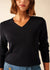 Frau in einem schwarzen SAINT JAMES Brehat Strickpullover mit V-Ausschnitt und blauen Jeans, dargestellt von den Schultern bis zur Taille.