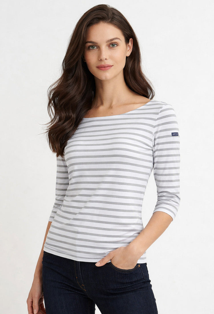 Frau mit langen braunen Haaren trägt das SAINT JAMES Garde-Cote Marinière Hemd in Grau und Weiß, gepaart mit dunklen Jeans.