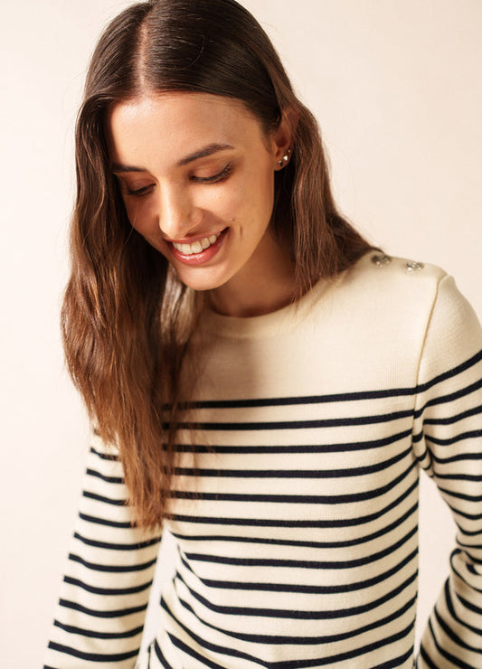Frau mit langen braunen Haaren lächelt, sie trägt den Pullover SAINT JAMES Marée in Creme mit schwarzen Streifen.