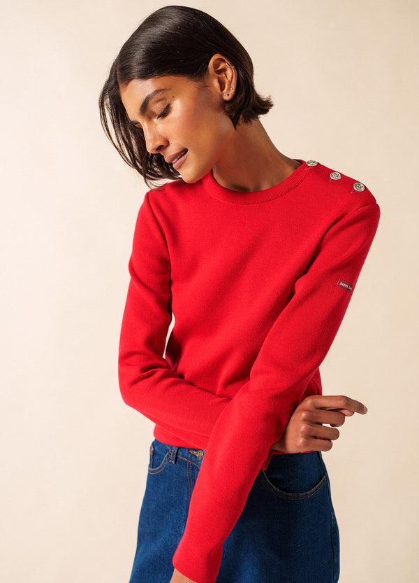 Frau trägt den roten Marée Damen-Marinpullover von SAINT JAMES mit silbernen Knöpfen und blauen Jeans.