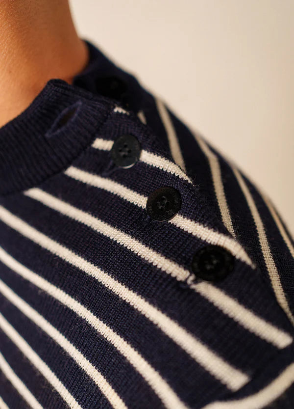 Nahaufnahme des SAINT JAMES Matelot, eines marineblauen Pullovers mit weißen Streifen und schwarzen Schulterknöpfen.