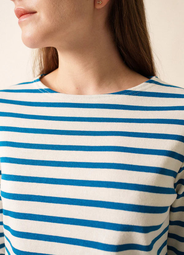 Frau trägt das SAINT JAMES Meridame, ein weißes Hemd mit blauen Streifen im Stil der Marinière, von links.