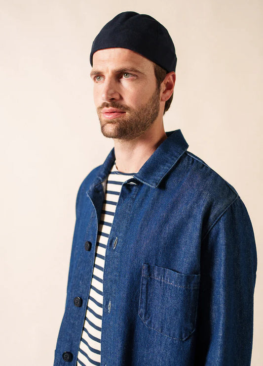 Mann in dunkler SAINT JAMES Miki Canva, gestreiftem Hemd und blauer Jeansjacke, der zur Seite schaut.