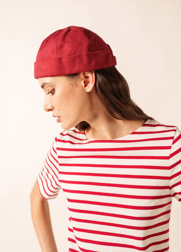 Frau mit rotem SAINT JAMES Miki Canva-Hut und rot-weiß gestreiftem Hemd, Blick zur Seite.