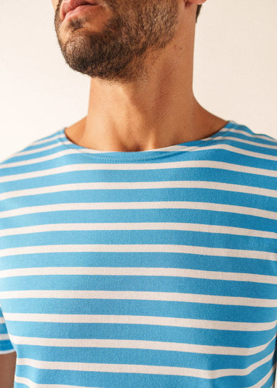 Ein Mann in einem blau-weißen SAINT JAMES Minquiers-T-Shirt, von den Schultern aufwärts gesehen, wobei ein Teil seines Gesichts sichtbar ist.