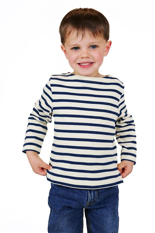 Lächelnder Junge in einem MOUSQUETON Mario Kid Kinder-Marinière aus Baumwolle, stehend vor einem weißen Hintergrund.