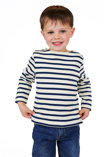 Lächelnder Junge in einem MOUSQUETON Mario Kid Kinder-Marinière aus Baumwolle, stehend vor einem weißen Hintergrund.