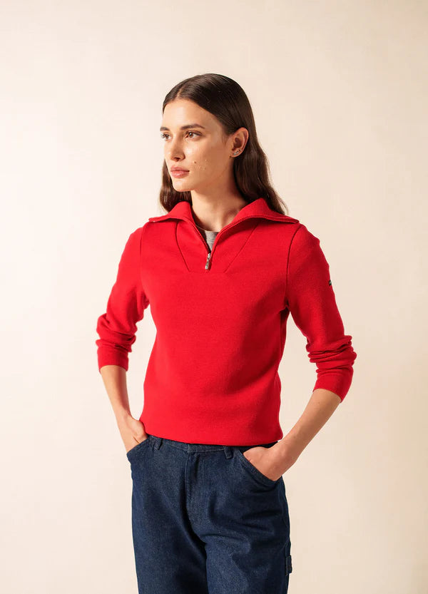 Frau trägt Passerelle Wollpullover mit Zipperkragen von SAINT JAMES und blaue Hose, Hände in den Taschen.