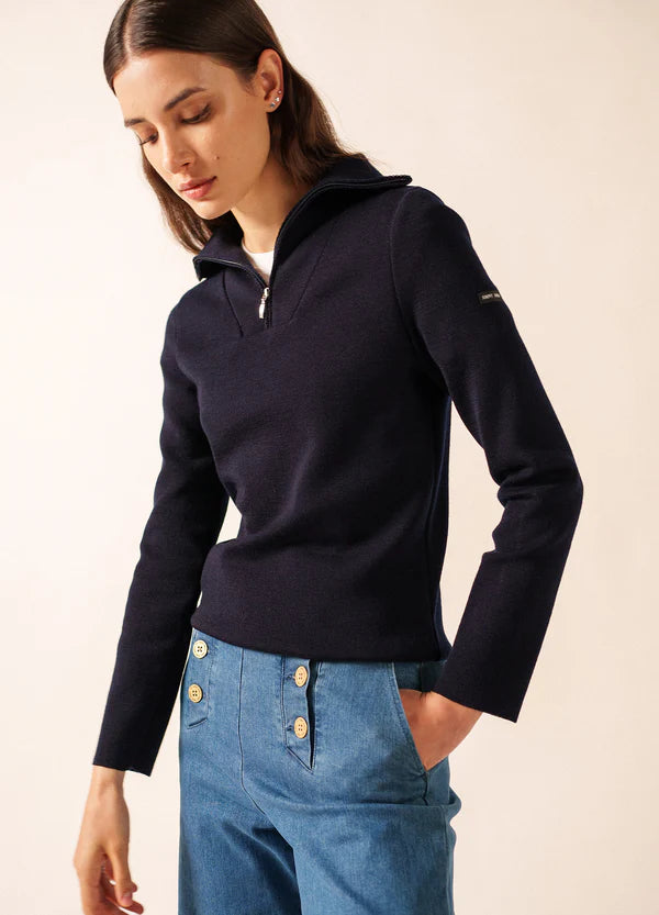 Frau trägt den SAINT JAMES Passerelle navy Zip-Sweater und high-waisted Jeans, schaut nach unten.