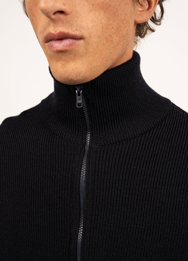 Nahaufnahme einer Person in einem schwarzen SAINT JAMES Quiberon-Rollkragenpullover mit Reißverschluss, der Hals und unteres Gesicht zeigt.