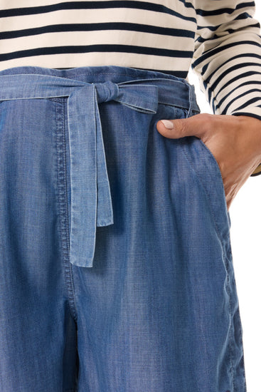 Person trägt ein gestreiftes Hemd und mousqueton Amandine blaue Lyocell Shorts, Hand in der Tasche, gezeigt von der Schulter bis zum Oberschenkel.