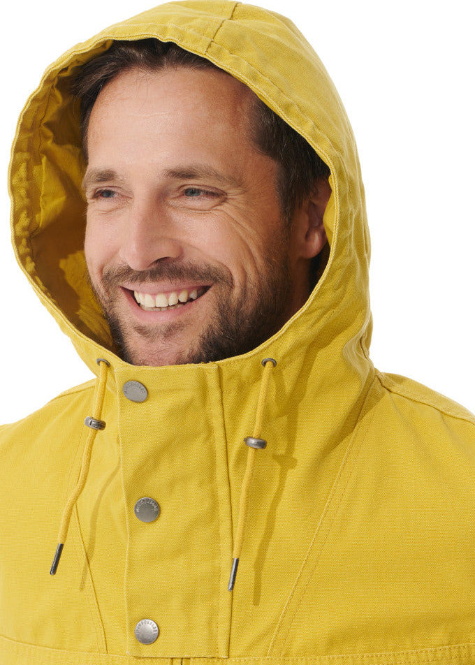 Lächelnder Mann in der gelben, wasserabweisenden MOUSQUETON Baden Kapuzenjacke mit aufgesetzter Kapuze vor weißem Hintergrund.