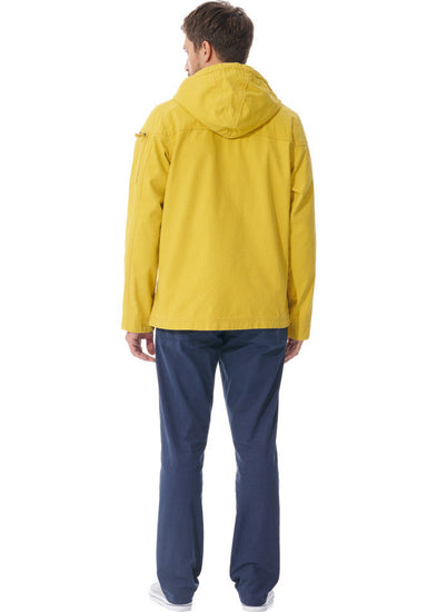 Mann in gelber, wasserabweisender MOUSQUETON Baden Jacke und blauer Hose vor weißem Hintergrund.