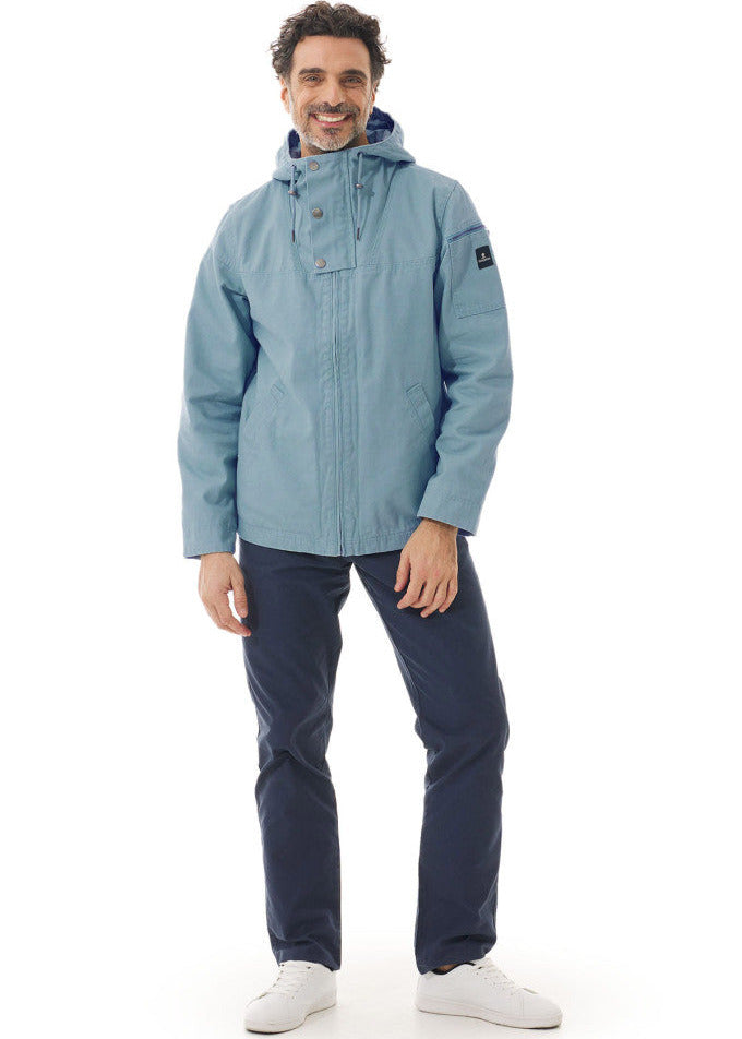 Mann in hellblauer Jacke, dunkler Hose und weißen Turnschuhen von MOUSQUETON Baden, lächelnd vor weißem Hintergrund.