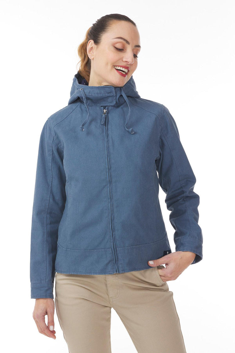 Frau in MOUSQUETON Fiona blauer Übergangsjacke Damen und beiger Hose, lächelnd, schaut zur Seite.