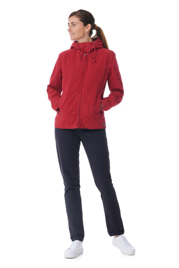 Frau trägt die rote Übergangsjacke Fiona von MOUSQUETON, schwarze Hose und weiße Sneaker vor weißem Hintergrund.